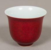 A Chinese porcelain wine cup With allover red glaze, blue painted mark to base. 6 cm high.