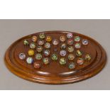 A large mahogany solitaire board Together with a set of hand blown coloured air twist marbles.