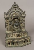 An Indian patinated bronze figure of deity Seated in the lotus position before a shrine. 29.