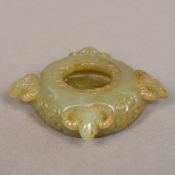 A Chinese carved pale green and russet jade brush washer Worked with rams' masks. 17.5 cm diameter.