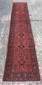 A wool runner The wine red field enclosing cruciforms and geometric motifs within stylised herati