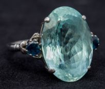 A 9 ct white gold aquamarine and sapphire ring The large oval facet cut aquamarine flanked by