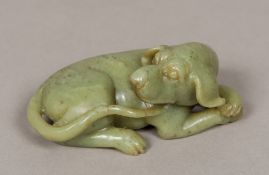 A Chinese carved green jade group Modelled as a recumbent dog. 12.5 cm long.