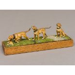A cold painted bronze group of three working dogs in various poses On a naturalistic cast base,