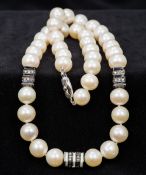 A pearl necklace The pearls interspersed with three enamel and diamond set spacers. 46 cm long.