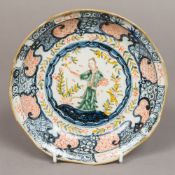 A Chinese porcelain dished plate Centrally worked with a figure within foliate sprays and variously