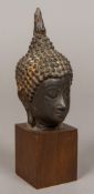 A Chinese cast bronze Buddha's head Later mounted on a wooden plinth base. 18 cm high overall.