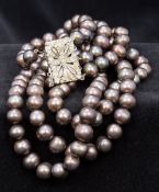 A Chinese freshwater lustre pearl three strand necklace With paste set white metal clasp.