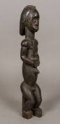 A large African tribal carved wooden figure Modelled seated and with brass stud inset eyes.