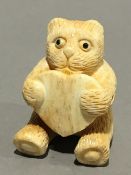 A bone netsuke formed as a bear with a heart