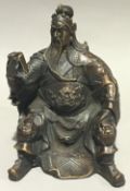 A Chinese bronze model of a seated deity reading a book