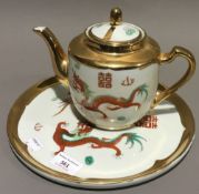 A Chinese porcelain teapot on stand decorated with dragons and a porcelain model of a dragon