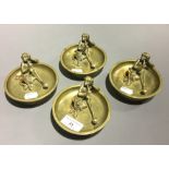 A set of four late 19th/early 20th century brass ash trays each mounted with a bronze smoking