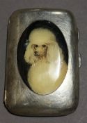 A silver cigarette case depicting a dog