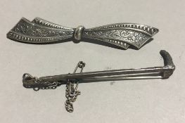 A silver riding crop brooch and another