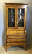 An early 20th century oak lead glazed top bureau bookcase