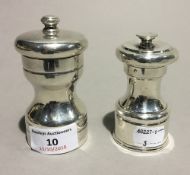 Two silver pepper grinders