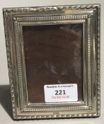 A small silver photograph frame and a silver desk clock