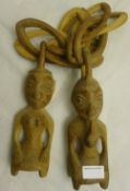 A pair of carved wooden Yoruba Ere Ibeji twin figures interlinked by a wooden chain and a pair of