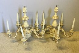 A pair of cream painted wooden chandeliers