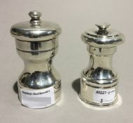 Two silver pepper grinders