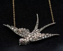 An unmarked diamond and ruby set pendant on an 18 ct gold chain Formed as a swallow in flight.