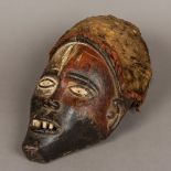 An African carved wooden tribal mask Mounted with a high headdress over the pierced eyes and mouth.