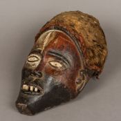 An African carved wooden tribal mask Mounted with a high headdress over the pierced eyes and mouth.