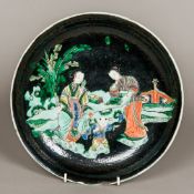 A 19th century Chinese famille noir dish Decorated with two female figures and a child in a garden