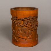 A Chinese carved bamboo brush pot Carved in the round with figures in various pursuits in a tree