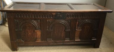 An 18th century carved oak coffer The hinged rectangular three panelled lid above the arch carved