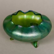 A Loetz iridescent glass footed bowl Of squat crimped form with three outswept legs.