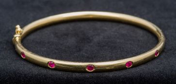 A Thurlow and Champness ruby set 18 ct gold bracelet Of hinged bangle form, boxed. 6.5 cm wide.