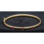 A Thurlow and Champness ruby set 18 ct gold bracelet Of hinged bangle form, boxed. 6.5 cm wide.