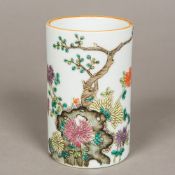 A Chinese porcelain brush pot Of circular section, worked with flowers issuing from a pierced rock,