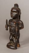 An African carved wooden tribal figure Formed as a male with bone inset eyes and holding a knife