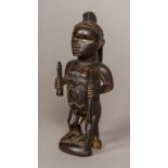 An African carved wooden tribal figure Formed as a male with bone inset eyes and holding a knife