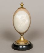 A carved and mounted emu's egg Carved to the front with a vignette of a kookaburra. 21.5 cm high.