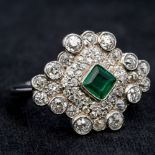 A platinum diamond and emerald cluster ring Of shaped navette form, centred with a single emerald.
