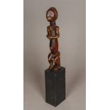 An African tribal carved wooden fertility figure Formed as a seated male with bead inset eyes,