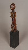 An African tribal carved wooden fertility figure Formed as a seated male with bead inset eyes,