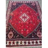 A wool rug The wine red field enclosing a central medallion,