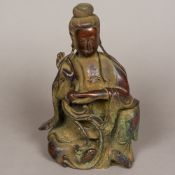 A Chinese patinated bronze model of Guanyin Modelled seated, holding a lily with a fish beneath,