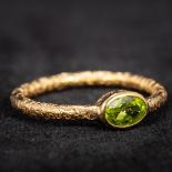 A 19th century unmarked gold peridot set ring The shank with all round engraved decoration.
