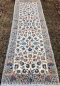 A Kashan wool runner The ivory field enclosing arabesque vines within floral border. 313 x 102 cm.