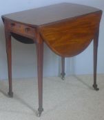 A George III mahogany crossbanded Pembroke table The oval twin flap top above the end frieze drawer,