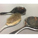 A silver and tortoiseshell mirror and two brushes