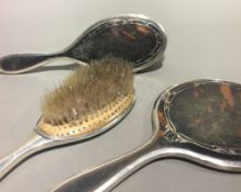 A silver and tortoiseshell mirror and two brushes