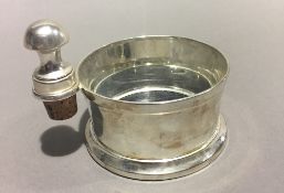 A silver plated bottle coaster with bottle stopper en-suite