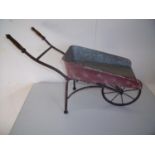 Metal constructed model of a vintage wheelbarrow with turned wood handles (overall length 65cm)